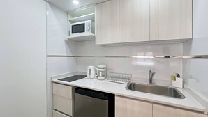 A modern kitchen with white cabinets, a stainless steel sink, a microwave, a coffee maker, and a dishwasher. - Modern & Cozy Studio San Telmo With Pool and Exclusive Services (Buenos Aires)