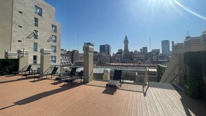 A rooftop terrace with lounge chairs and a view of a city skyline. - Modern & Cozy Studio San Telmo With Pool and Exclusive Services (Buenos Aires)