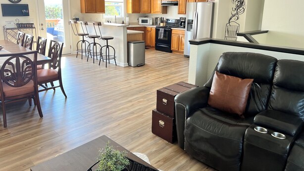 A modern kitchen with wooden cabinets, a stainless steel refrigerator, and a dining area with a wooden table and chairs.