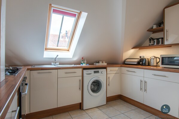 Une cuisine compacte équipée d’un lave-linge, d’un four à micro-ondes et d’un grille-pain.