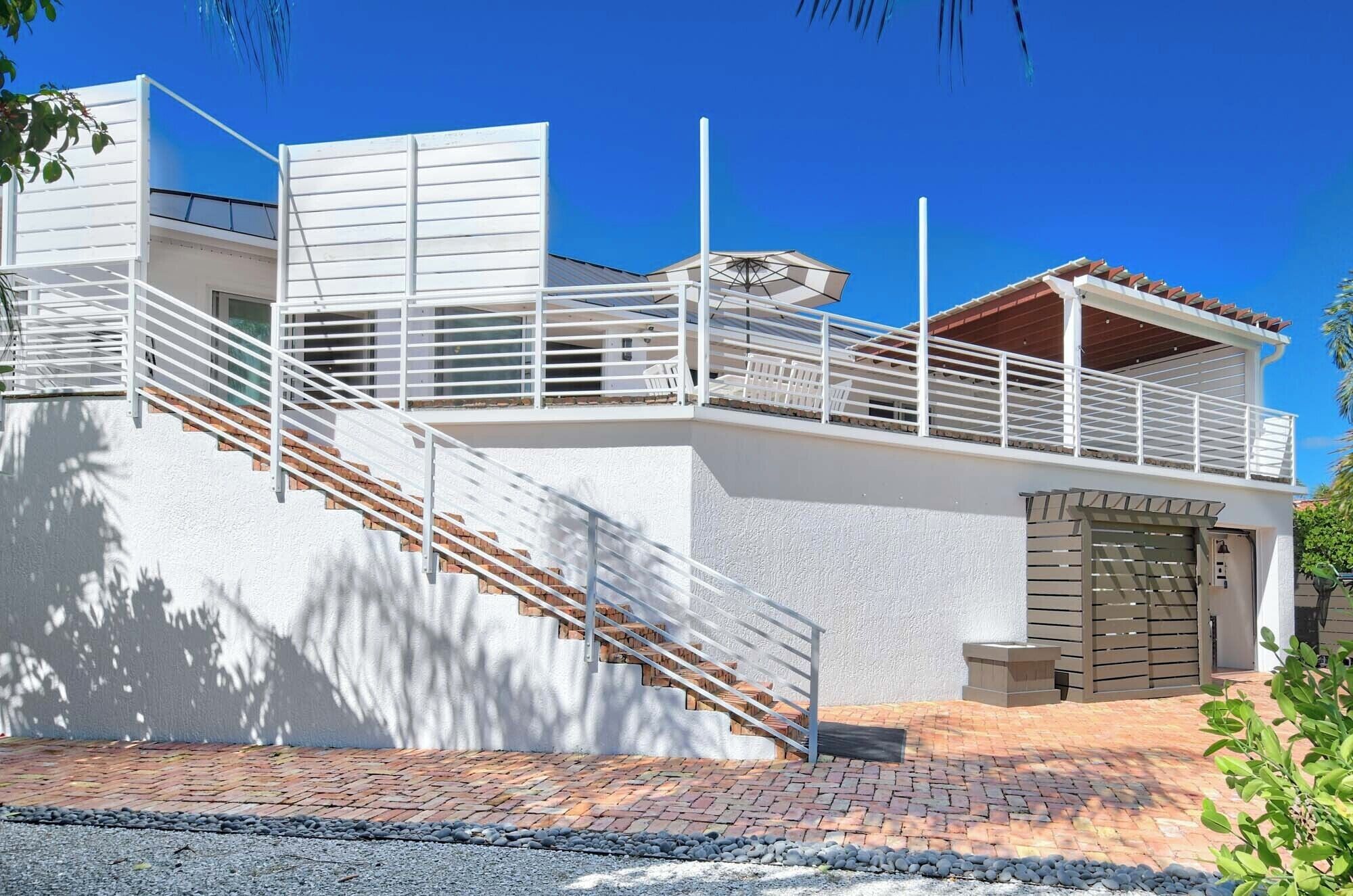 A modern building with a staircase leading to a balcony, a covered outdoor area, and a large wooden door.