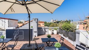 Eine Dachterrasse mit Sitzgelegenheiten im Freien, einem großen Sonnenschirm und einem Schild für 'EFFE LUXURY PALACE'.