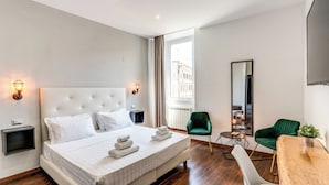 Ein modernes Hotelzimmer mit einem großen Bett, einem Schreibtisch, einem grünen Sessel und Blick auf die Stadt.