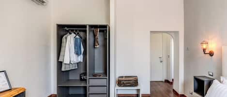 A modern hotel room with a bed, a wardrobe, a bedside table, and a nightstand.