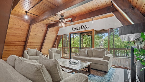A cozy, wooden-floored living area with a large window, a ceiling fan, and a 'lakelife' sign.