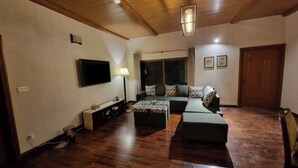 Una sala de estar con un sofá, un reposapiés y un televisor de pantalla plana.
