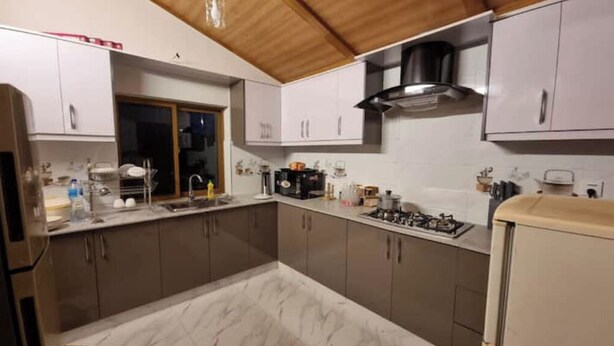 A kitchen with white cabinets, a marble countertop, a stove, and a sink.
