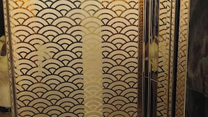 A room with a green carpet, a decorative panel with a wave pattern, and a mirror reflecting part of the room. - Hotel Gloab Residency Near Delhi Airport (New Delhi)