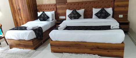 A hotel room with two wooden beds, each with white bedding and black floral pillows.