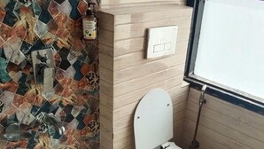 A bathroom with a tiled floor, a toilet, a sink, and a window. - Hotel Gloab Residency Near Delhi Airport (New Delhi)