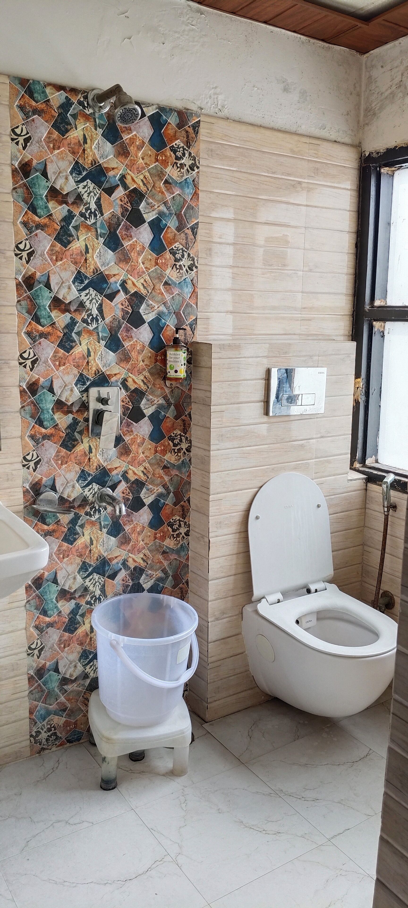 A bathroom with a tiled wall, a toilet, a sink, and a shower.