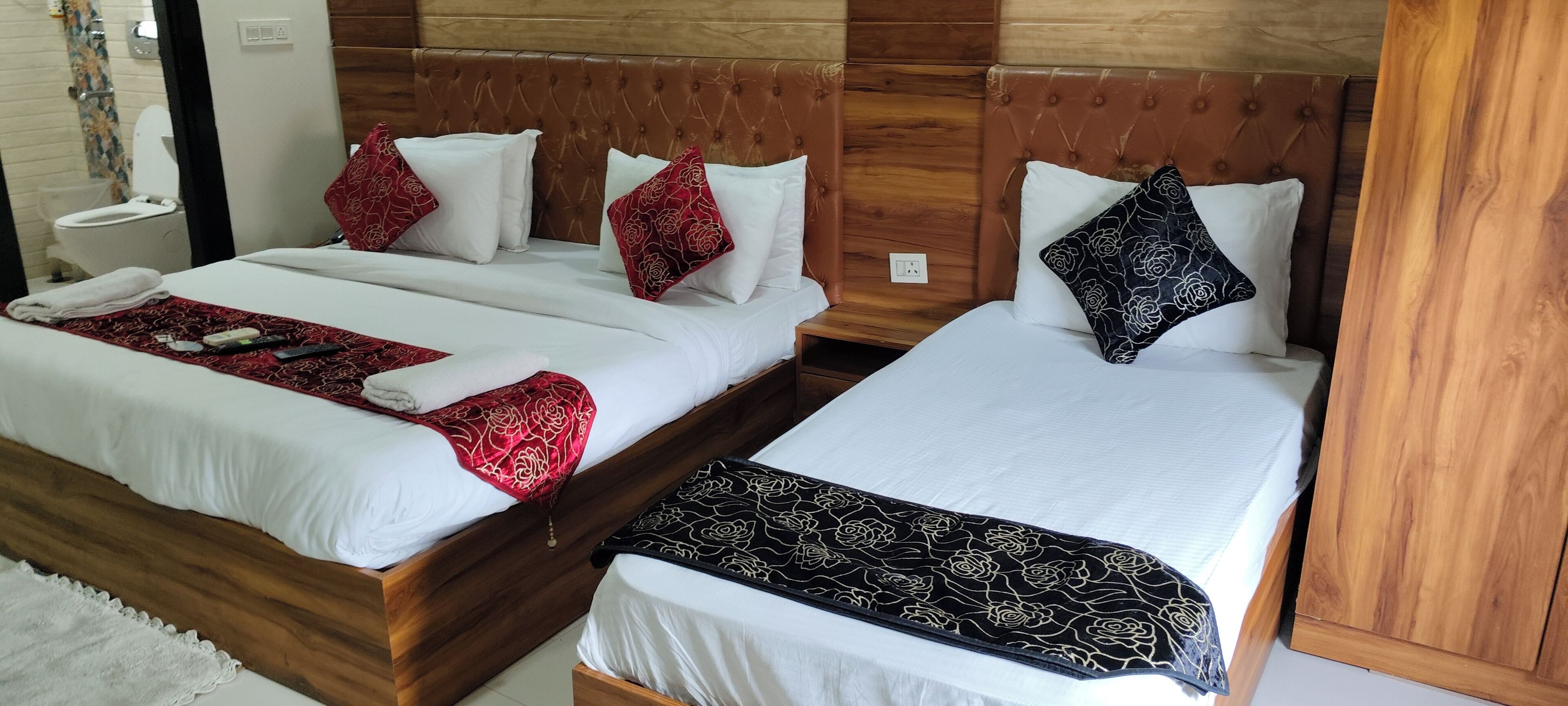 Ein Hotelzimmer mit zwei Betten, jeweils mit einem hölzernen Kopfteil, weißer Bettwäsche und Kissen mit Blumenmuster.
