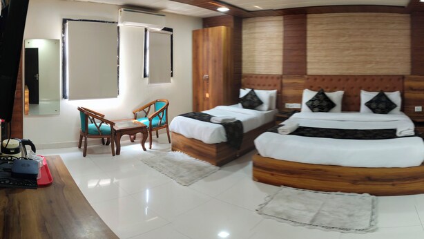 A bedroom with two beds, a wooden headboard, a chair, and a small table. - Hotel Gloab Residency Near Delhi Airport (New Delhi)