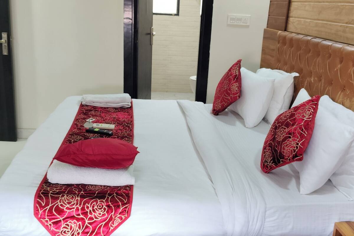 Une chambre d’hôtel avec un grand lit, une tête de lit en bois et une petite table de chevet.