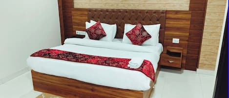 Ein ordentlich gemachtes Bett mit einer rot-weißen Bettdecke, einem Holz-Kopfschild und zwei Zierkissen.
