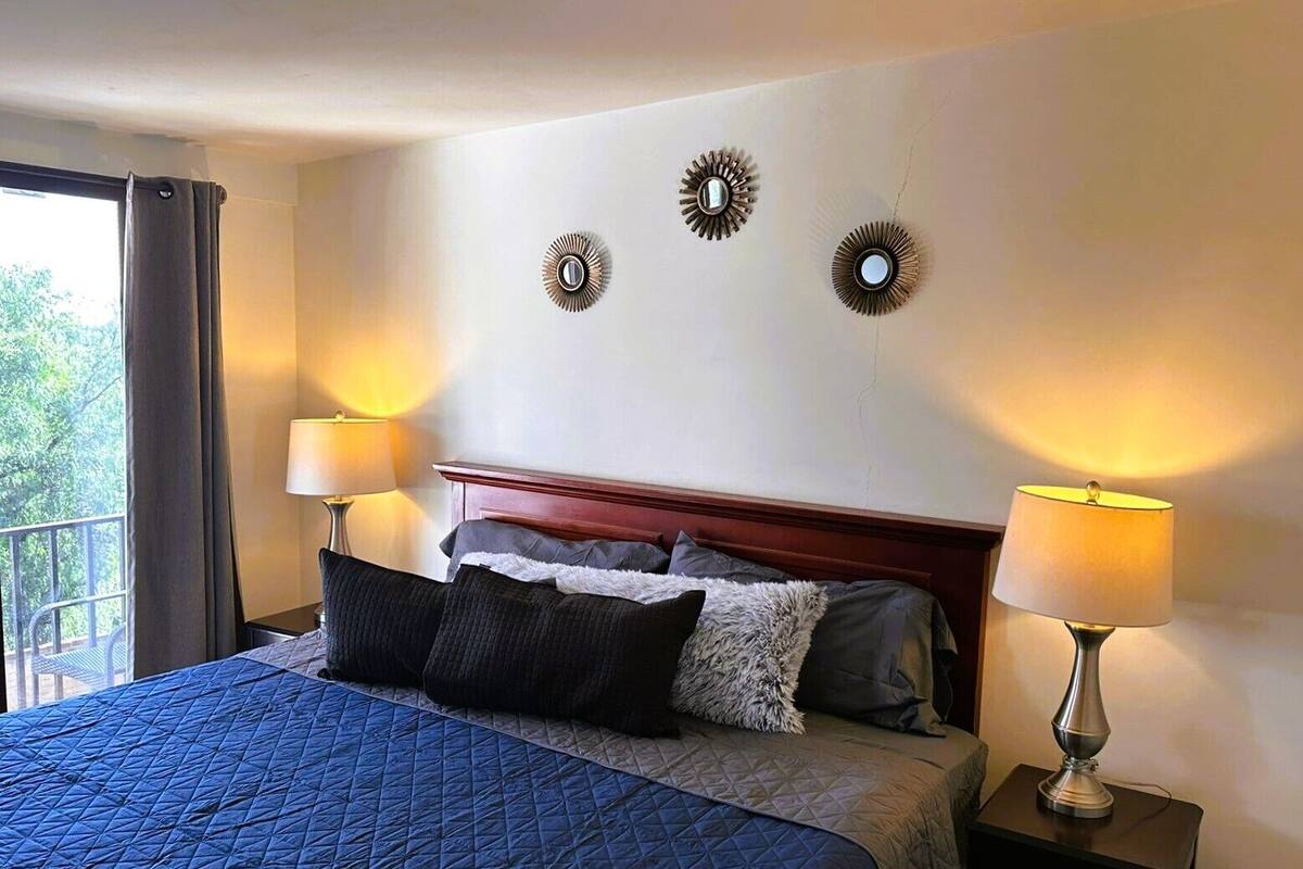 Una habitación de hotel con una cama grande, dos lámparas de noche y apliques decorativos.