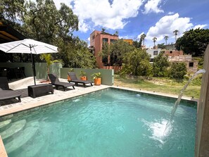 Una piscina al aire libre, sombrillas, sillones reclinables de piscina