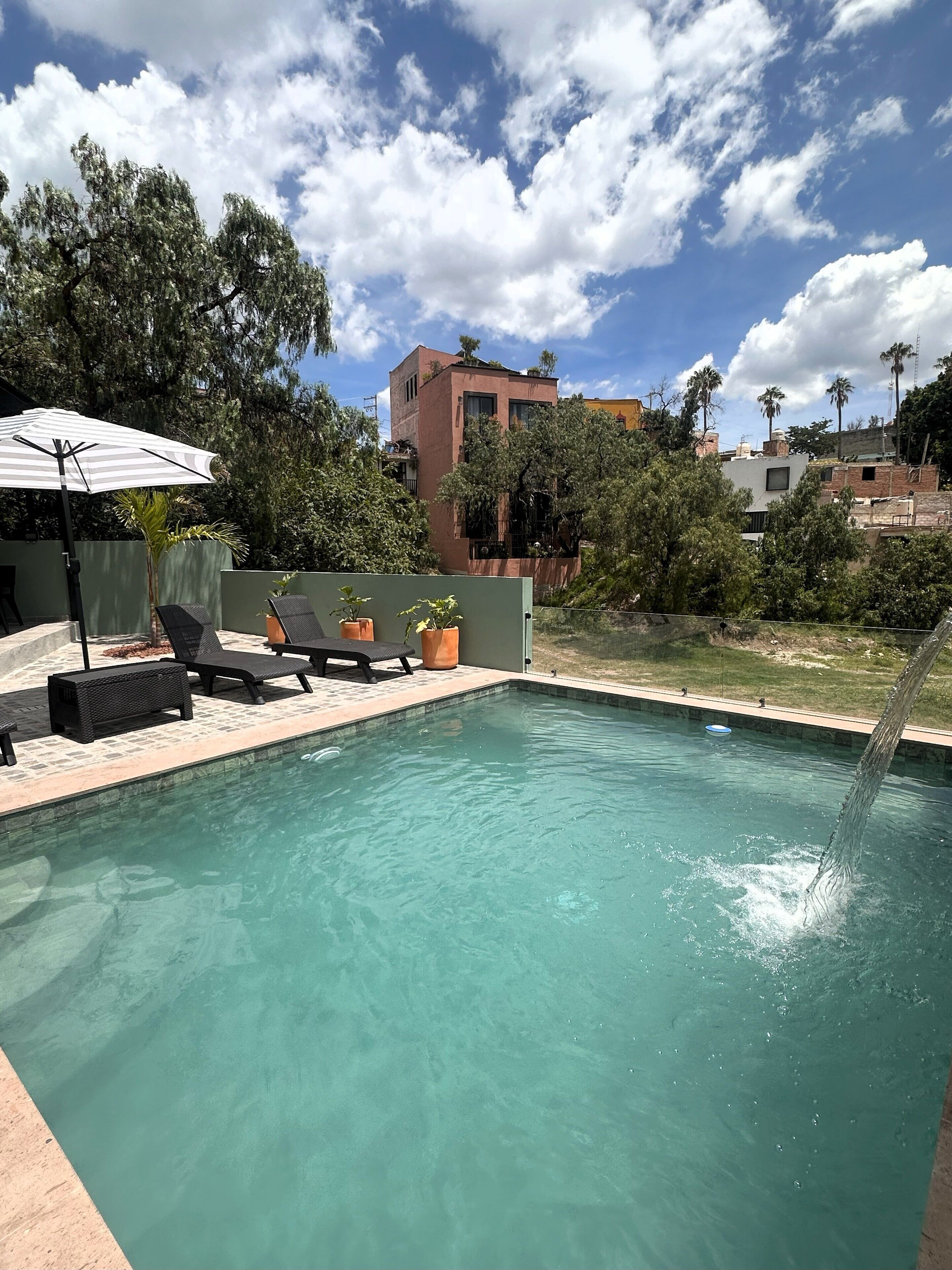 Una piscina al aire libre, sombrillas, sillones reclinables de piscina