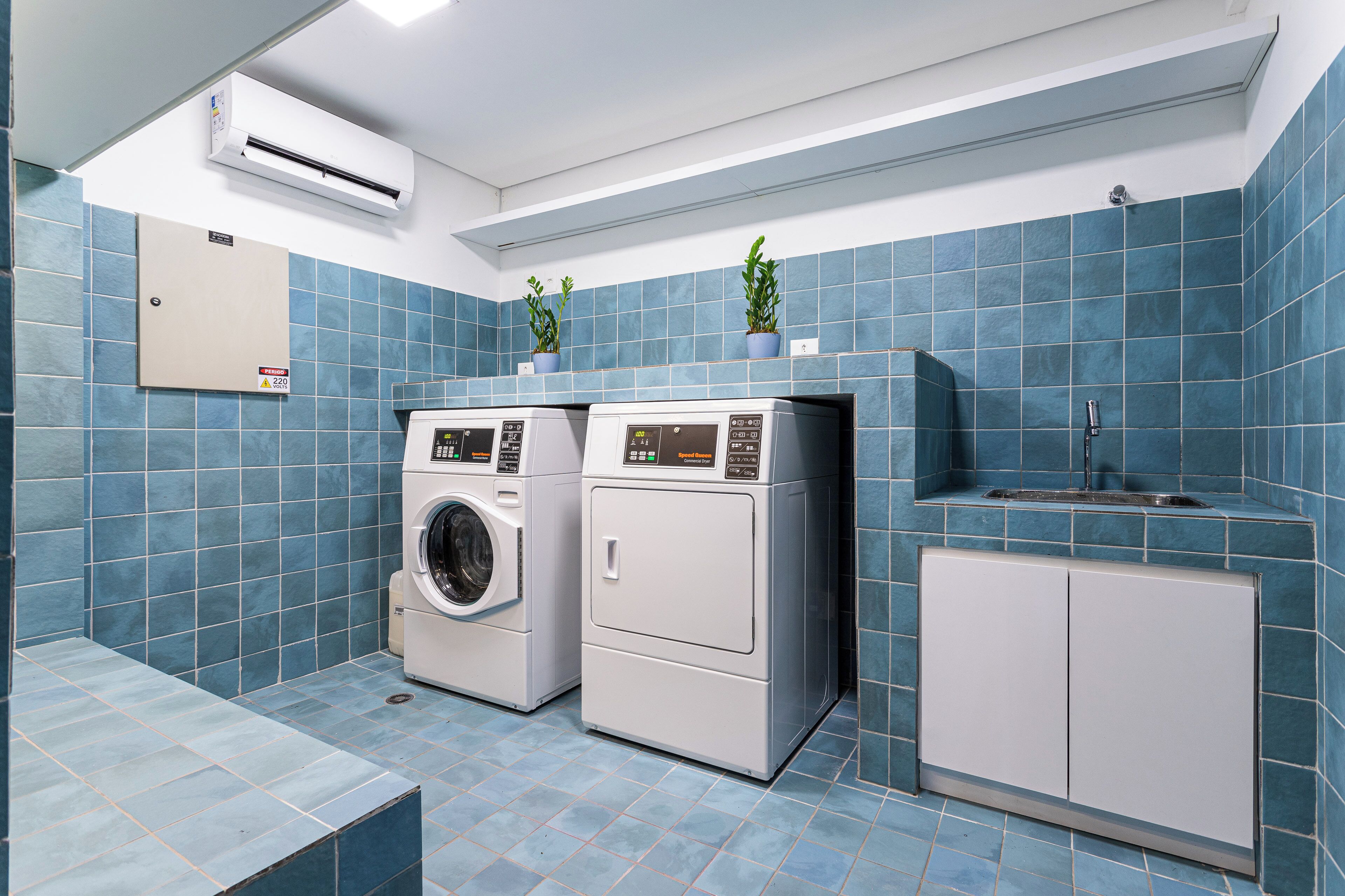 A laundry room with two washing machines, a dryer, and a cabinet.