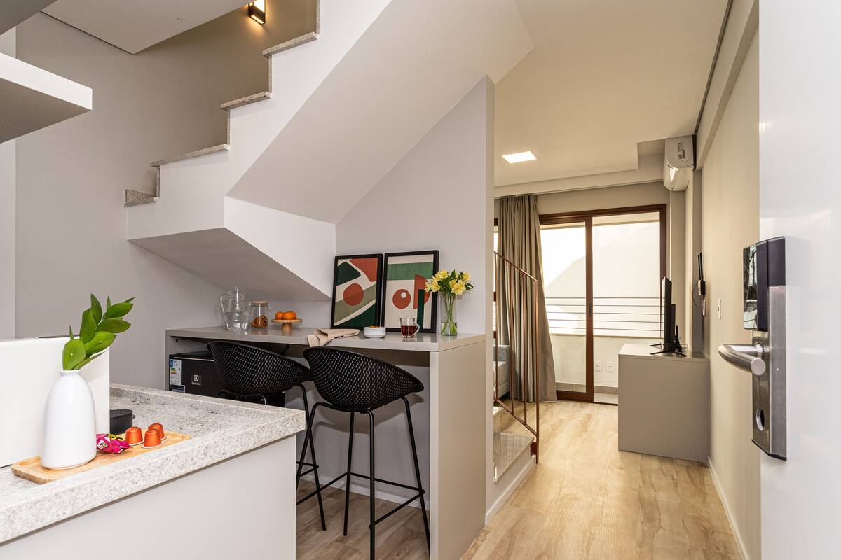 Eine moderne Küche mit Barbereich, einer Treppe und Blick auf den Balkon.