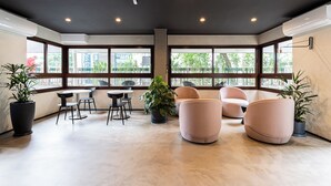 A modern interior with large windows, a round table, and several seating areas. - Next Bela Cintra by Viva - Prédio completo com wi-fi próximo ao metrô Consolação e ao MASP (São Paulo)