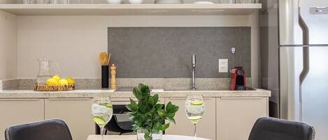 A modern kitchen with a round dining table, two chairs, a plant, and a refrigerator.