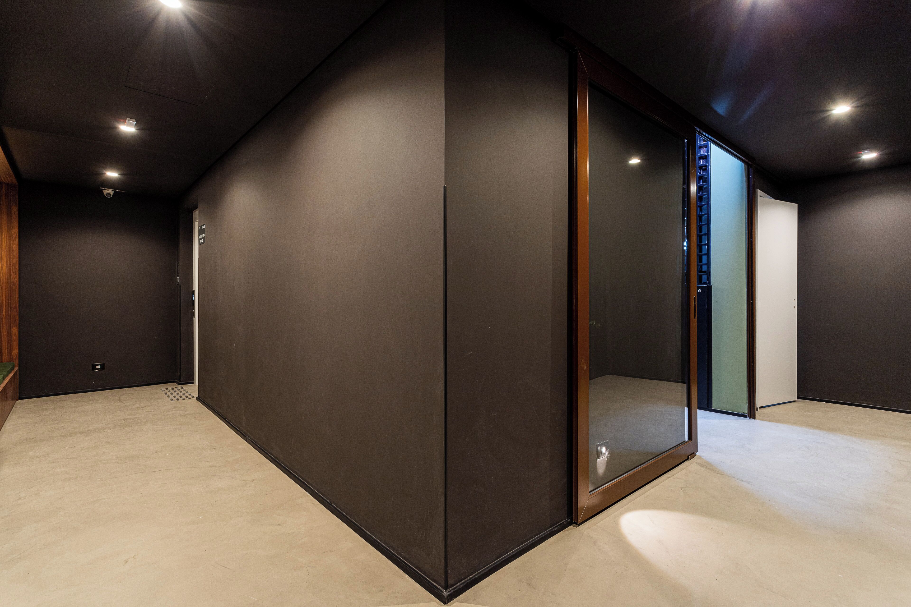 Een moderne, gedimde kamer met een grote schuifdeur, een klein raam en een sobere wand.