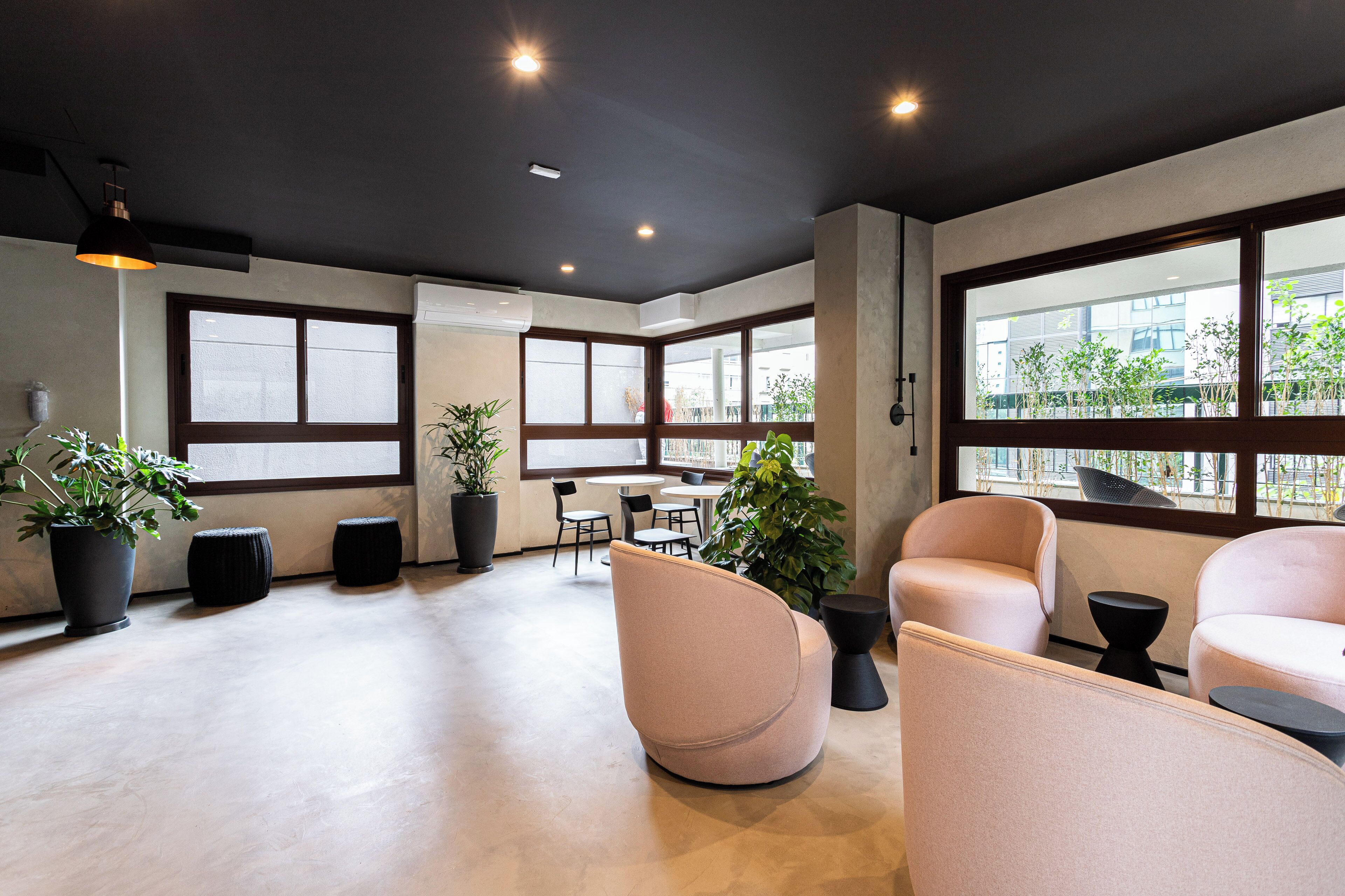 A modern interior with large windows, seating areas, and potted plants.