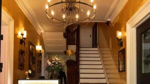 Et hotel lobby med reception, trappe og lysekrone.