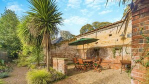 A patio area with brick flooring, a table with chairs, and a green umbrella. - Blofield Cottage - UK48095 (Norwich)