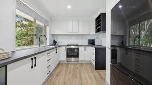 A modern kitchen with white cabinets, a stainless steel stove, and a microwave.