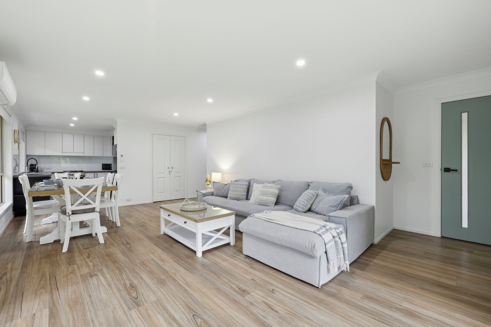 A modern living room with a grey sofa, white chairs, and a coffee table.