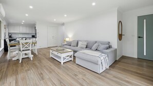 A modern living room with a grey sofa, white chairs, and a coffee table.