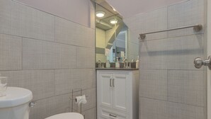 A modern bathroom with a toilet, a vanity with a mirror, and a shower area.