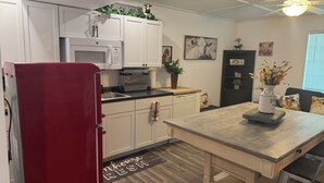 Une cuisine de taille réduite avec des meubles blancs, un four à micro-ondes et un réfrigérateur rouge.