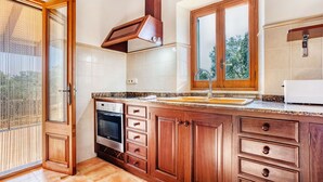 Eine Küche mit Holzausstattung, einem Einbauofen und einem Fenster mit Blick ins Grüne.
