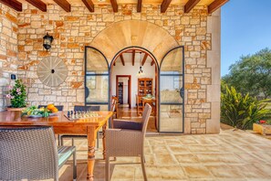 A stone-walled patio with a dining table and chairs, a chessboard, and a view into the interior. - Talaia Vella by dracmallorca (Santanyi)
