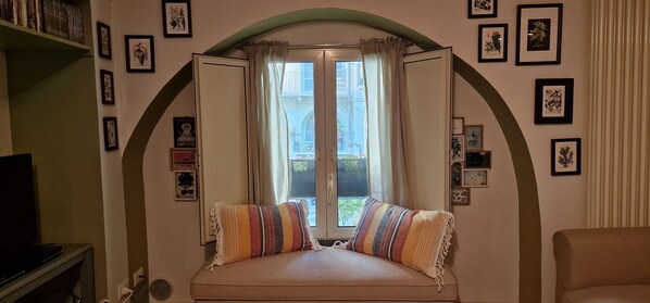 A cozy room with a window, a sofa, and a TV.
