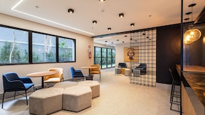 A modern interior with seating areas, a bar, and large windows. - Zoom Santa Cecília by Viva - Prédio próximo à estação Marechal Deodoro e Fácil acesso ao Memorial da América Latina (São Paulo)