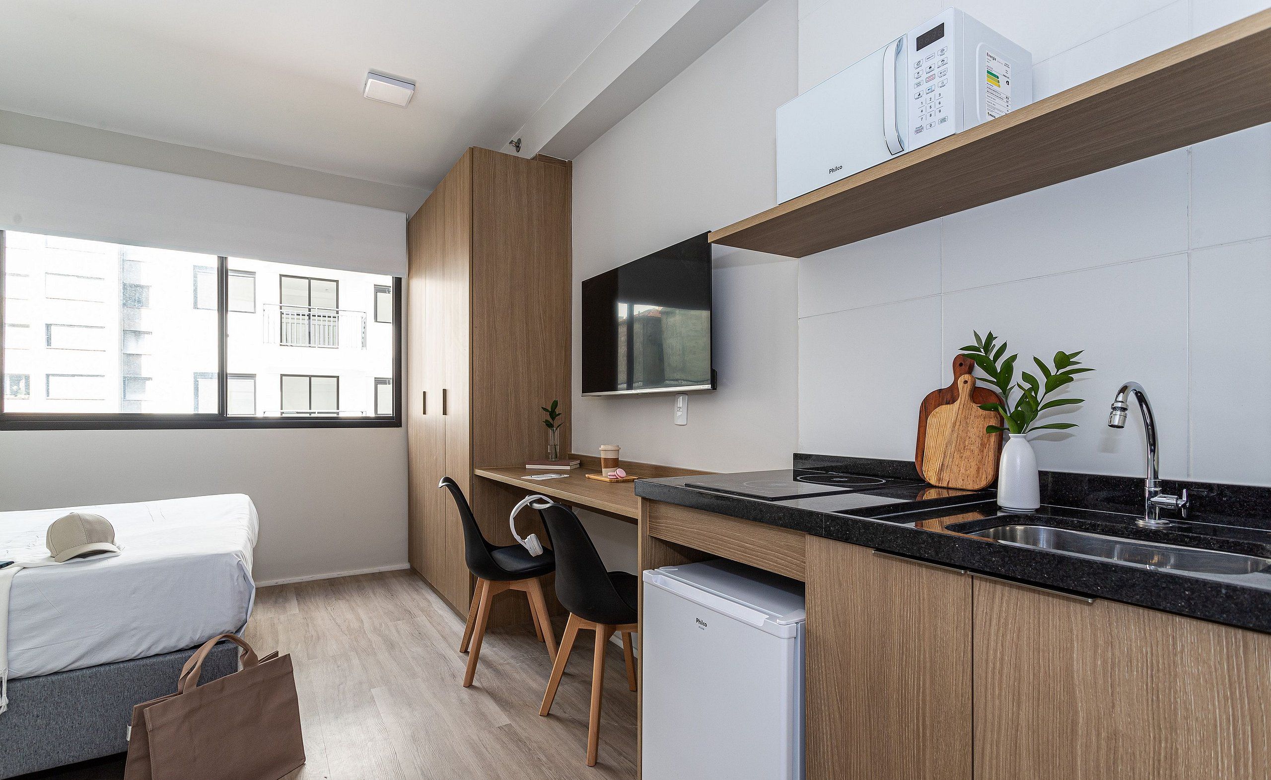 A modern kitchen with a built-in stove, a sink, and a flat-screen TV mounted above the counter.