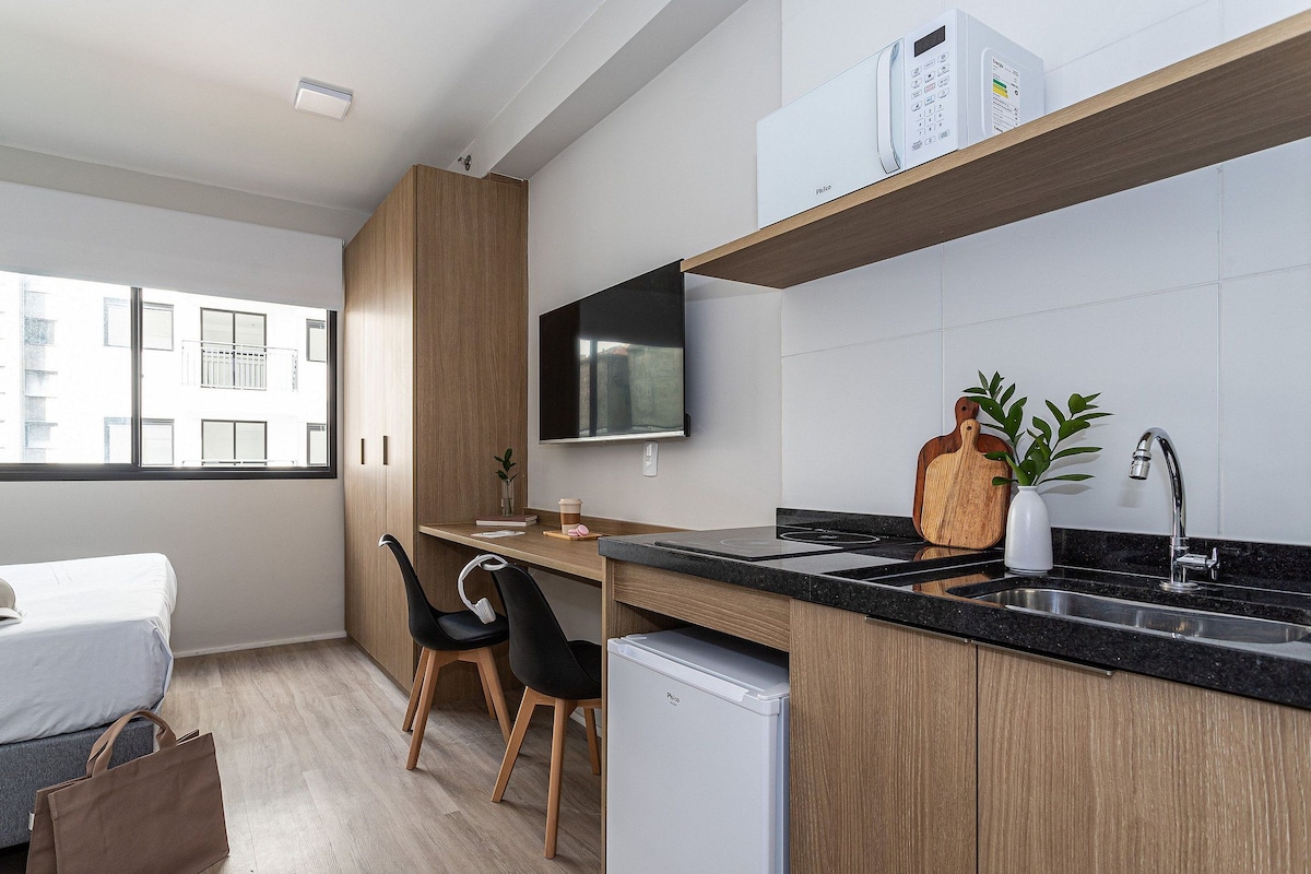 A modern kitchen with a built-in stove, a sink, and a flat-screen TV mounted above the counter.