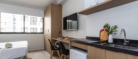 A modern kitchen with a built-in stove, a sink, and a flat-screen TV mounted above the counter.