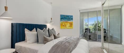 Un dormitorio moderno con una cama grande, un ventanal que da a un balcón y un cuadro en la pared.