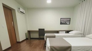 Une chambre d’hôtel avec deux lits, un bureau, une chaise et un tableau au mur.