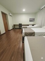 Una habitación de hotel con dos camas, un escritorio, una silla y un cuadro en la pared.