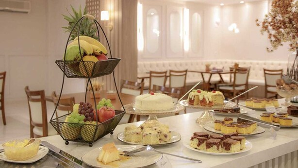 A buffet table with various desserts and fruits, including cakes, pies, and a fruit basket.