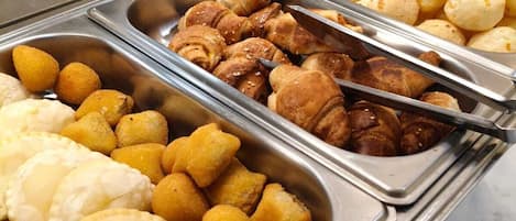 A buffet with various food items including pastries and bread.