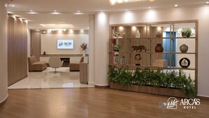 A modern hotel lobby with a reception desk, seating area, and a decorative wall with various items.