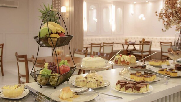 Une table de buffet proposant divers desserts et fruits, notamment des gâteaux, des tartes et un panier de fruits.