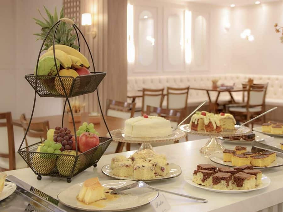 A buffet table with various desserts and fruits, including cakes, pies, and a fruit basket.